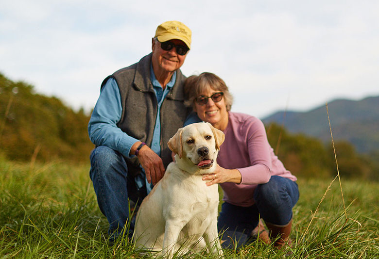 Man and woman smile lovingly with young white labrador